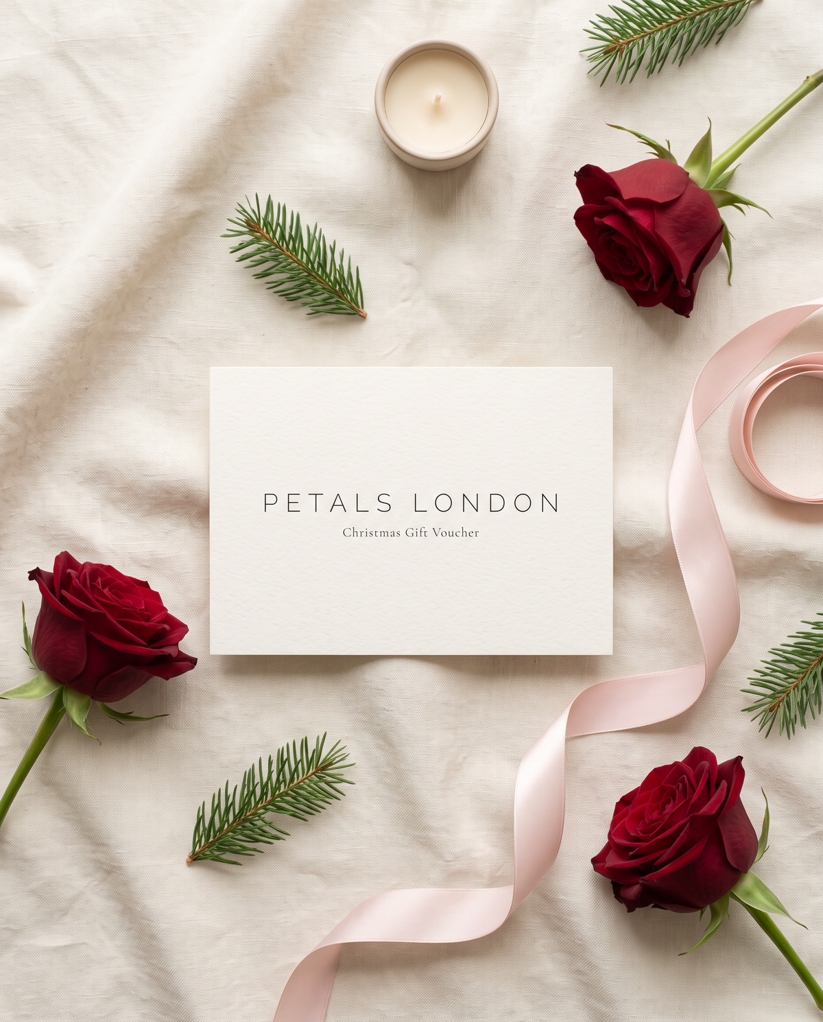 Petals London Christmas Gift Voucher flat lay with red roses, fir and pink ribbon