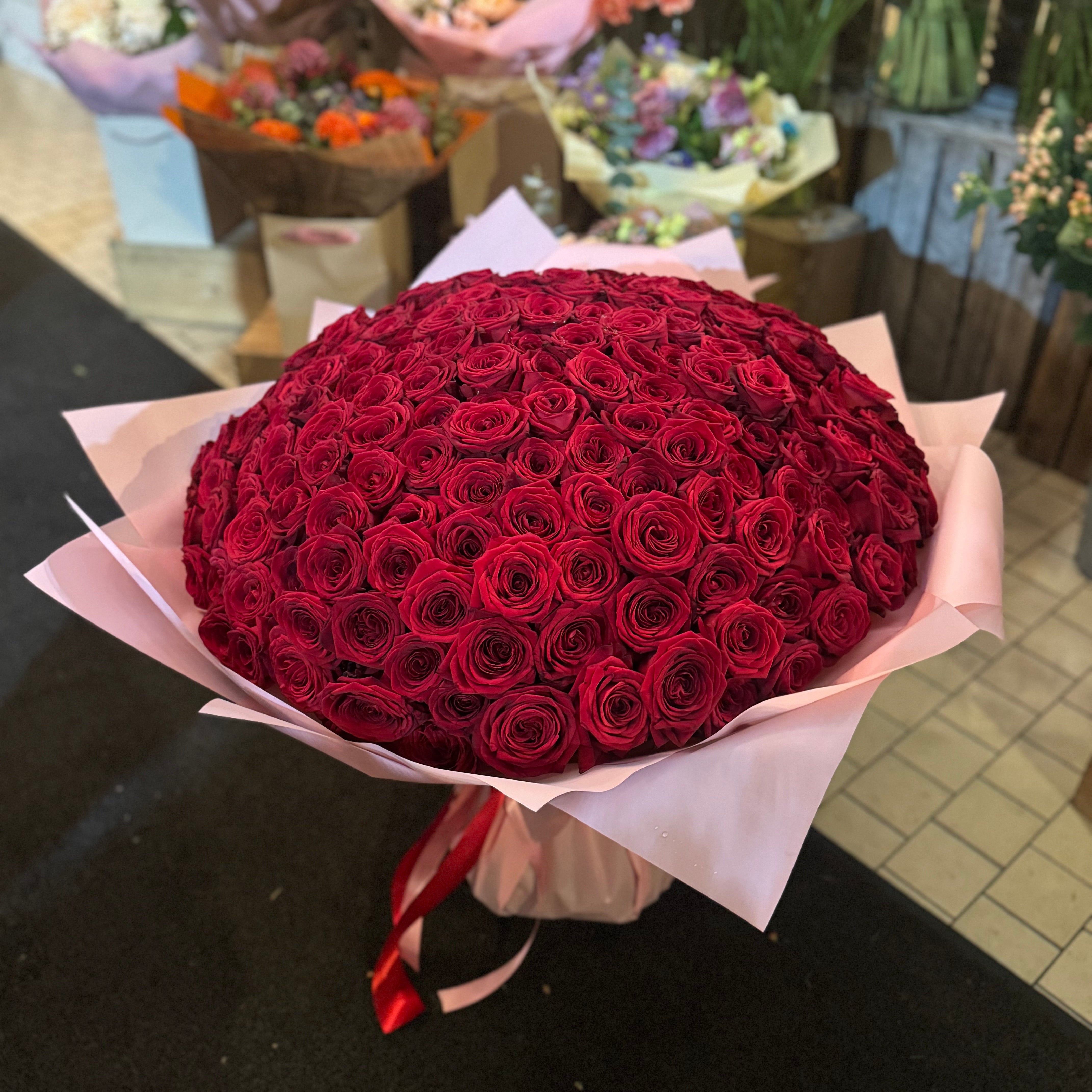 Bouquet of red roses on a dark surface with other flowers in the background