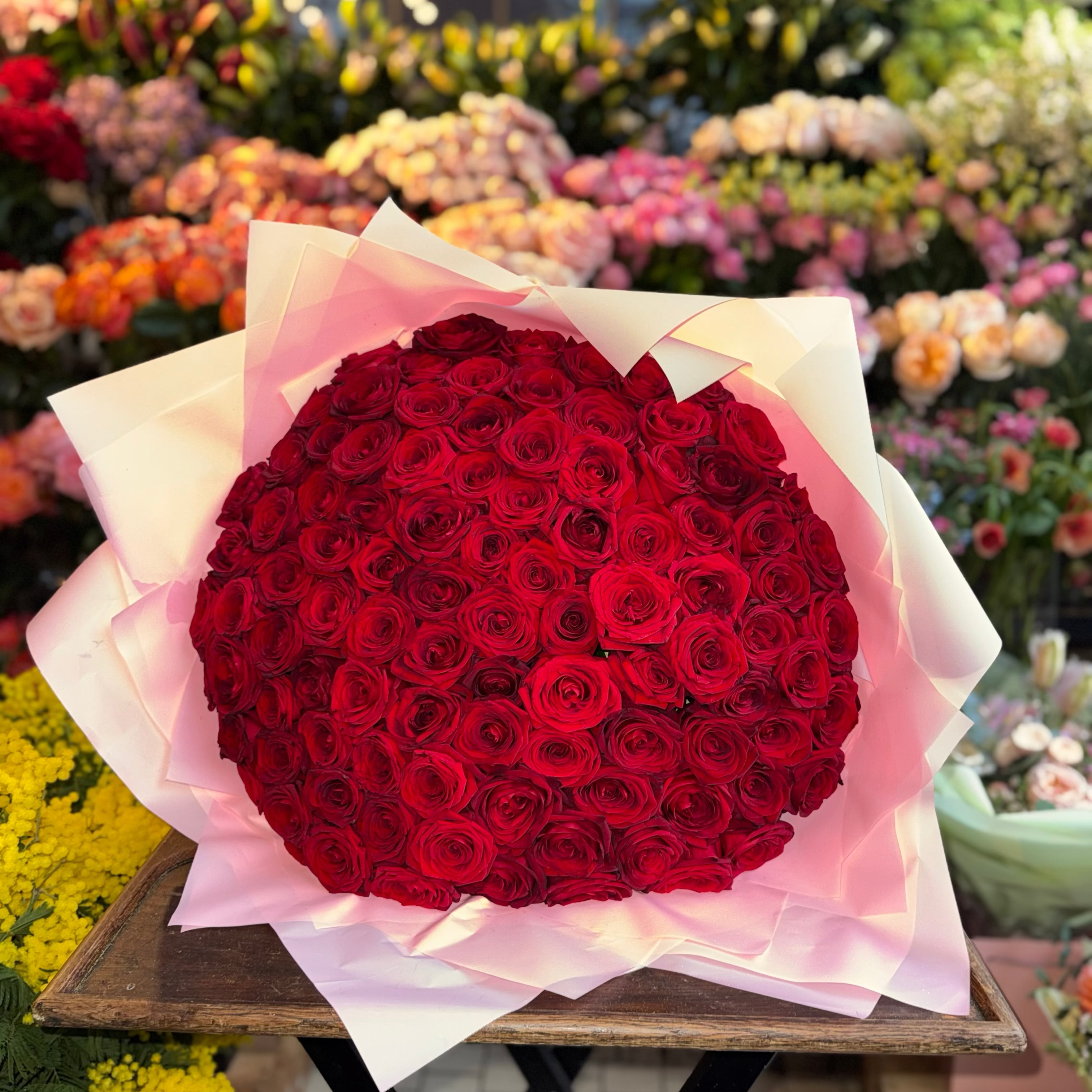 Bouquet of red roses on a wooden table with a flower shop background