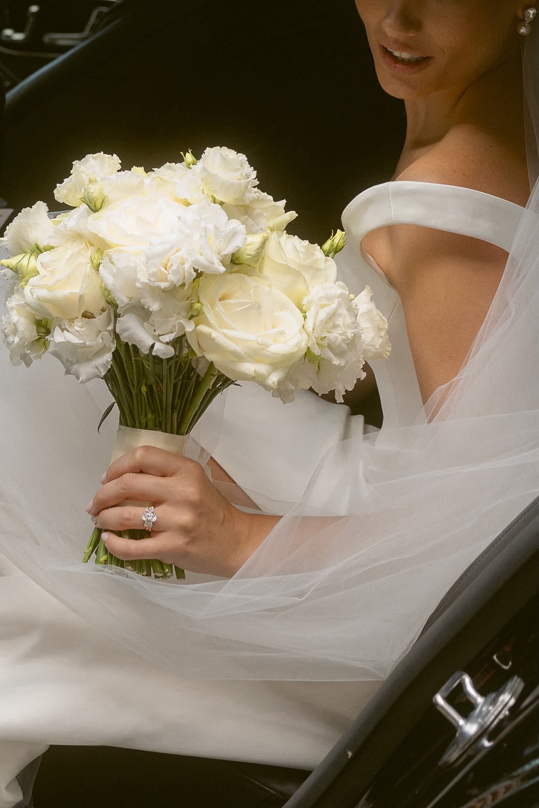 Bride in car holding white rose bouquet