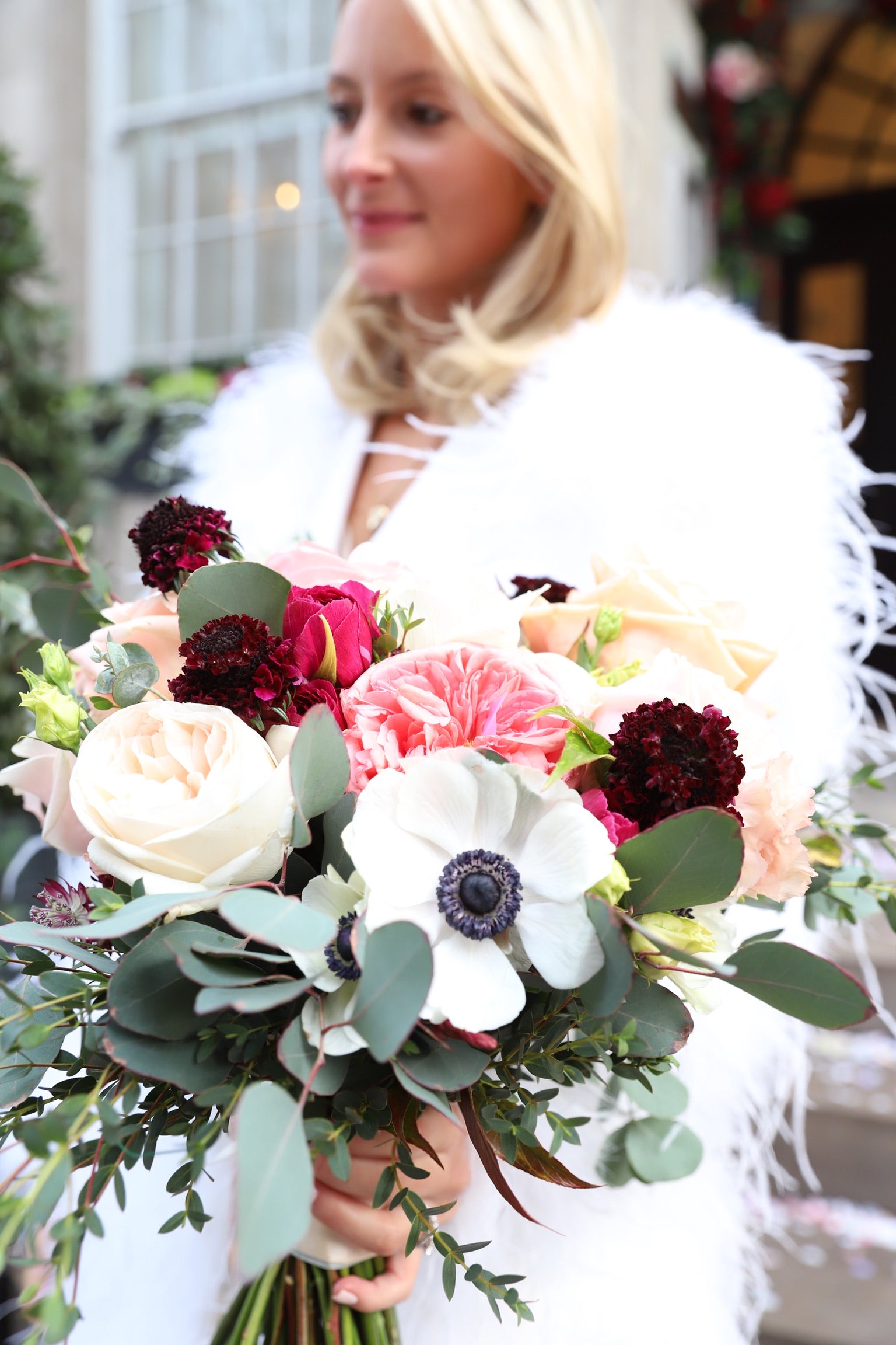 Bride in white feather wrap holding vibrant mixed bouquet