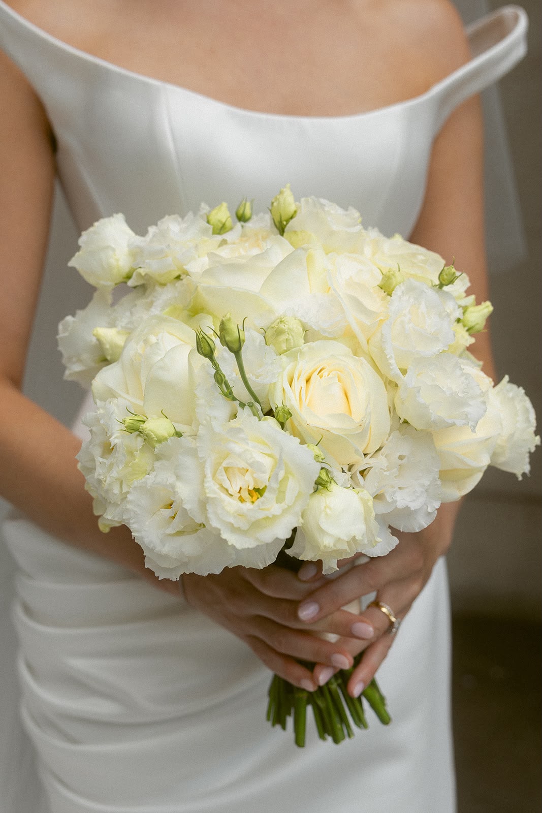 White and cream bridal bouquet held by bride in satin gown